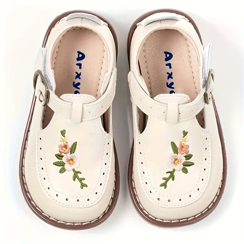 A pair of children's shoes placed on a soft, light-colored surface, showing a side view with a simple, durable design.