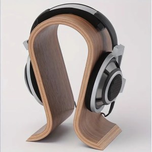 A sleek modern electronic device on a clean white desk with a cable, headphones, and a soft blue glow from the screen.