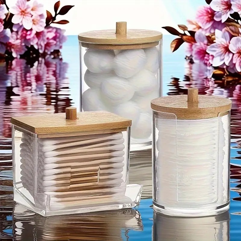 A soft, natural lighting scene with a white ceramic bottle, a wooden comb, a folded cotton towel, and fresh green leaves on a clean countertop.