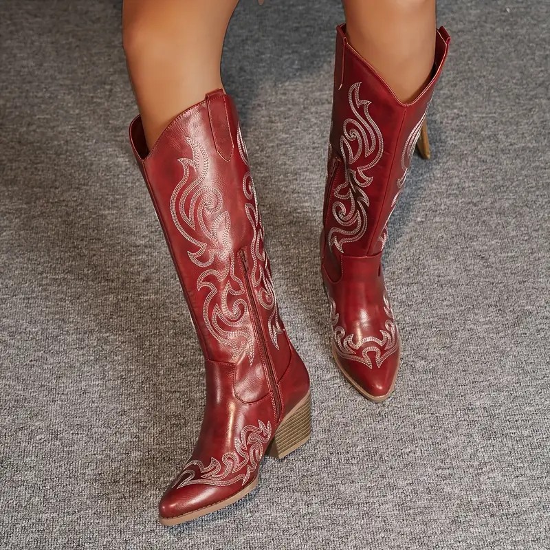 A pair of women's knee high boots shown from a slight angle, standing on a clean neutral background, with a smooth outer finish and a low block heel.